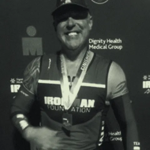 Boyd Myers at an Ironman finish line wearing his finisher medal